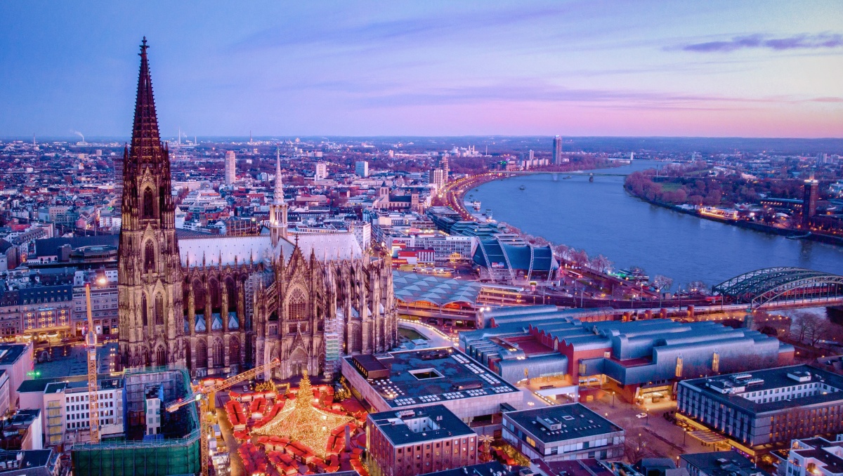 Cologne Cathedral and the Rhine River seen from above at sunset.